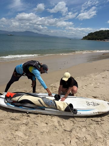 Instructor y alumno armando el equipo de windsurf en la playa antes de la clase