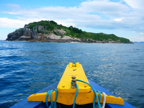 Ilha do Xavier vista da proa amarela do barco, com mar azul e céu aberto
