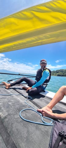 Alumno sentado en la red del catamarán Hobie Cat con chaleco salvavidas durante la clase