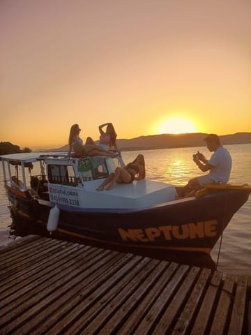 Barco Neptune atracado no trapiche com passageiros vendo o pôr do sol