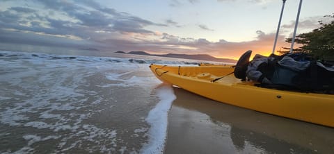 Kayak amarillo en la orilla del mar, con la espuma de las olas en la arena al amanecer