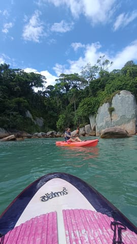 Red kayak near rocks and forest in calm water in Florianópolis