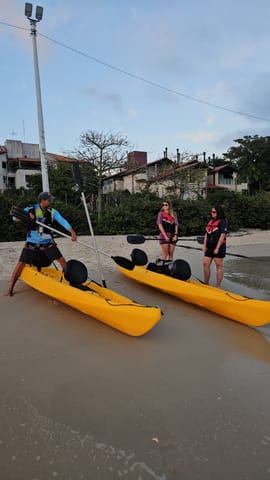Yellow kayaks on the beach sand with the group and paddles before the tour departs